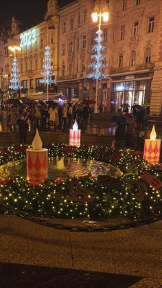 people are standing in the middle of a circle with christmas lights on it at night