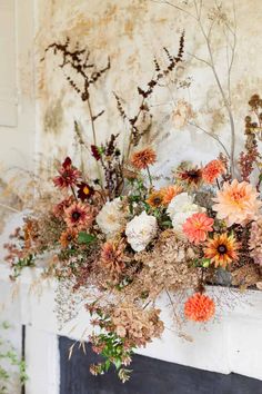 an arrangement of flowers is sitting on the fireplace mantel