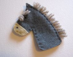 a felt horse head hanging from the side of a wall with white and gray paint