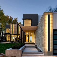 a modern house with steps leading to the front door and side entrance at night time