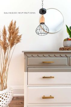 a white dresser with drawers and a mirror on the wall next to some plants in a basket