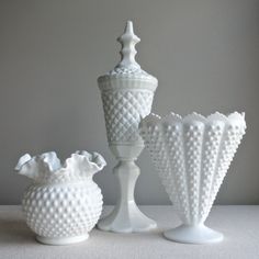 three white vases sitting next to each other on a table