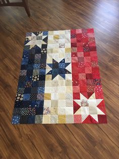 a red, white and blue quilt sitting on top of a wooden floor