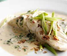 a white plate topped with fish covered in sauce