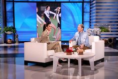 two women sitting in white chairs talking to each other on the set of an episode