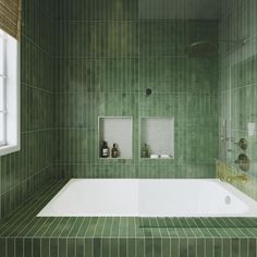 a green tiled bathroom with a bathtub and shower