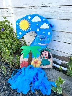 a blue and white stuffed animal sitting on top of a wooden bench next to plants