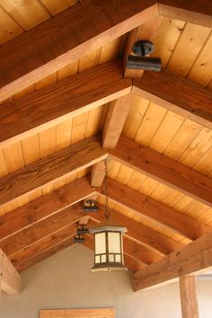 a light hanging from the ceiling in a room with wood paneling and wooden beams