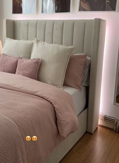 there is a bed with pink sheets and pillows on the headboard in this bedroom