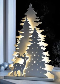 a lighted christmas tree in front of a window with the light on it's side