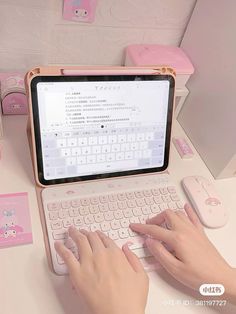 a person is typing on a laptop keyboard with pink accessories around her and holding the mouse in their hand