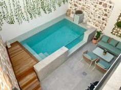 an aerial view of a swimming pool and patio area with lounge chairs, potted plants, and stone walls