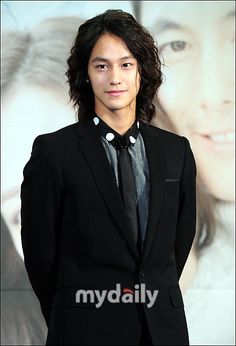 a young man in a suit and tie posing for the camera with his hands in his pockets