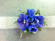 a bouquet of blue flowers sitting on top of a white ribbon