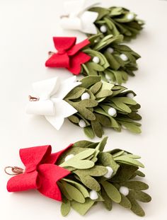 three christmas wreaths are lined up on a white surface with red and green felt bows