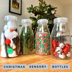 four glass jars filled with christmas candy and santa clause decorations on top of a wooden table