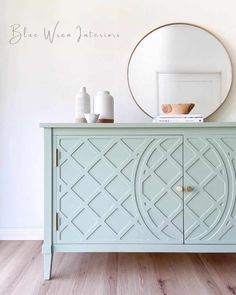 a green cabinet with an oval mirror above it and two vases on the side