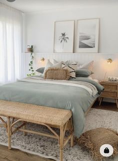 a bed sitting in a bedroom next to a window with white curtains and pillows on top of it