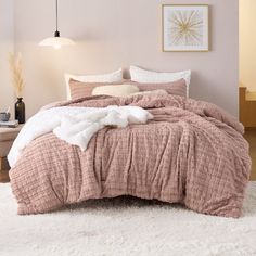 a bed with pink comforter and pillows on top of white rugs in a bedroom