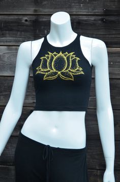 Gold Lotus Flower Fitted Crop Top - Women's Yoga Top - Festival Clothing This comfortable black fitted crop top features a double sided lotus flower design. The front has a large print in shinny metallic gold, and the back has a column of three smaller lotus flowers printed in glow in the dark. This Lotus flower is an original hand drawn image. The dark image shows the tank under a blacklight that is charging the glow in the dark ink.95% Cotton / 5% SpandexMade in the USAAvailable in sizes:SMALL