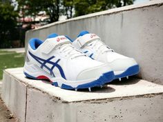 a pair of white and blue shoes sitting on top of a cement wall