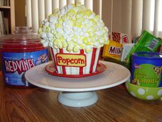 there is a cake that has popcorn in it and other snacks on the table next to it