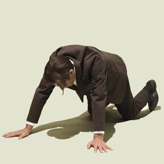 a man in a suit and tie is on the ground with his hands behind his head