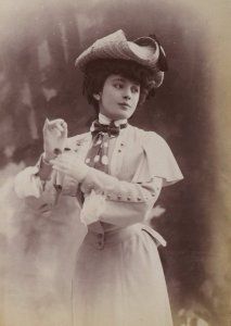 an old photo of a woman with a cat in her hand and wearing a hat