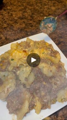 a white plate topped with pasta and meat covered in sauce on top of a counter