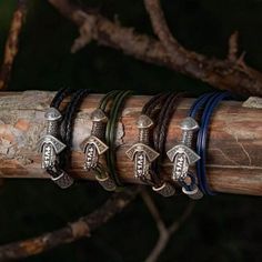 four different bracelets on top of a wooden stick in front of a tree branch