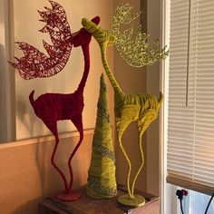 three metal sculptures are sitting on top of a wooden table in front of a window