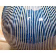 a blue and white striped vase sitting on top of a wooden table next to a tile floor