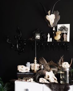 a black room with skulls, candles and other items on the shelf in front of it