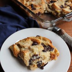 a white plate topped with a piece of cake next to a pan of baked goods