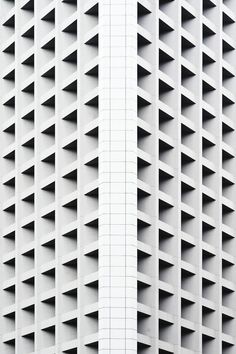 the side of a tall building with white bricks on it's sides and windows