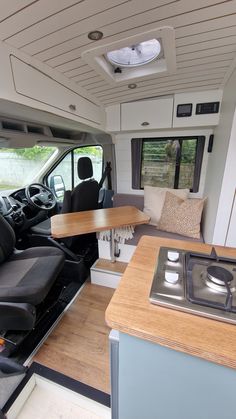 an interior view of a camper van with wood table and bench in the foreground