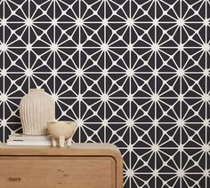 a white vase sitting on top of a wooden dresser next to a black and white wall