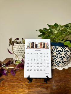 a calendar sitting on top of a wooden table next to potted plants