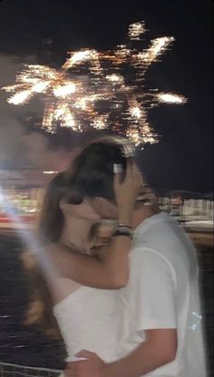 a man and woman embracing each other in front of fireworks