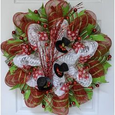 a christmas wreath with red and green mesh, bells and decorations on the front door