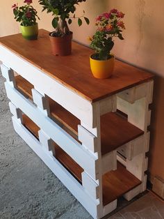 three potted plants are sitting on top of a wooden shelf that is made out of pallets