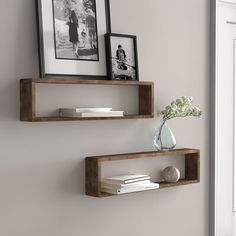 two wooden floating shelves on the wall with pictures and flowers in vase next to them