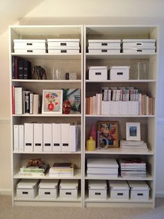 a white bookcase filled with lots of books next to boxes and containers on top of each shelf