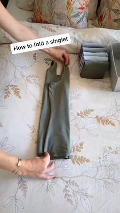 a woman is holding her pants on the bed with an ad taped to it that reads, how to fold a singlet