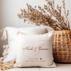 a white pillow sitting on top of a table next to a basket filled with flowers