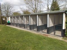 a group of cages sitting in the middle of a grass covered field next to a building