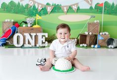 a baby boy sitting on the floor in front of a golf themed backdrop and cake