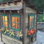 a small wooden house with windows and flower boxes