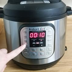 a hand points at an instant pot with the timer on it's display screen