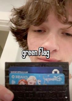 a boy holding up a credit card with the words green flag on it in front of his face